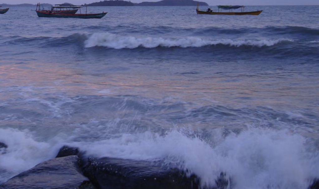 Image of tides at sunset with boats in distance.